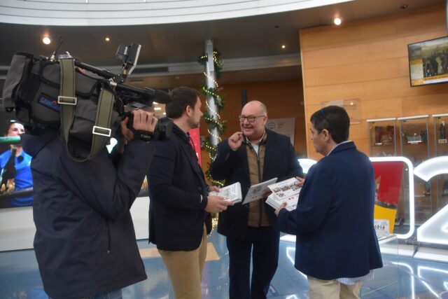 Imagen. Un cámara de televisión graba a José María Calasanz, gerente de Somontano Social, conversando con Jesús Alijarde, de Ibersyd y con Isabel Calderón, responsable de Impresión y ensobrado de Somontano Social, en las instalaciones de CARTV.