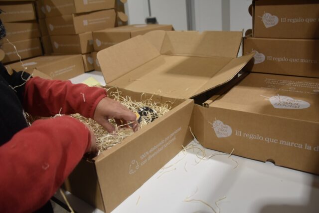 Imagen. Primer plano de unas manos trabajando en la preparación de uno de los lotes de Navidad para empresas de más de 50 trabajadores del proyecto 'Dale Valor Social' que ha impulsado la Fundación AltoAragón Integración (FAI) a través de Somontano Social, su Centro Especial de Empleo.
