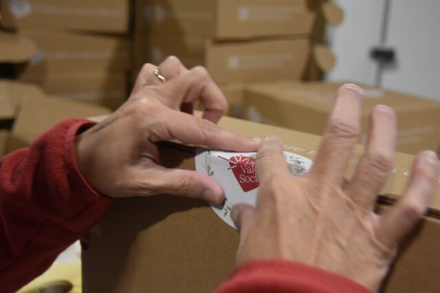 Imagen. Primer plano de unas manos ultimando el packaging de uno de los lotes de Navidad para empresas de más de 50 trabajadores del proyecto 'Dale Valor Social' que ha impulsado la Fundación AltoAragón Integración (FAI) a través de Somontano Social, su Centro Especial de Empleo.