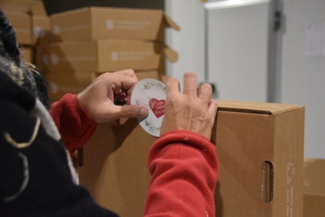 Imagen. Primer plano de unas manos ultimando el packaging de uno de los lotes de Navidad para empresas de más de 50 trabajadores del proyecto 'Dale Valor Social' que ha impulsado la Fundación AltoAragón Integración (FAI) a través de Somontano Social, su Centro Especial de Empleo.