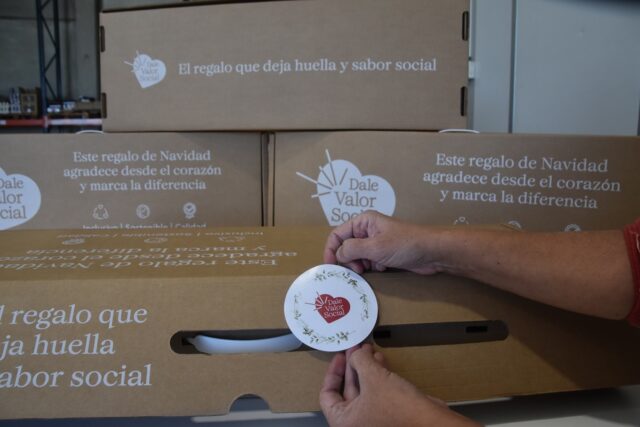 Imagen. Primer plano de unas manos ultimando el packaging de uno de los lotes de Navidad para empresas de más de 50 trabajadores del proyecto 'Dale Valor Social' que ha impulsado la Fundación AltoAragón Integración (FAI) a través de Somontano Social, su Centro Especial de Empleo.