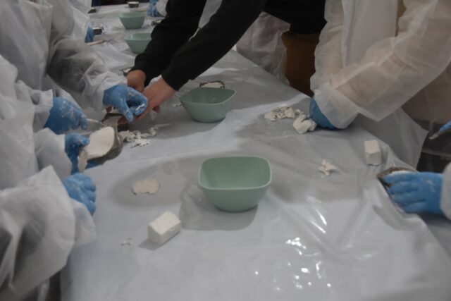 Imagen. Primer plano de las manos de varios escolares trabajando la arcilla en un molde en el taller de modelado de Molithe, marca propia de Somontano Social CEE.