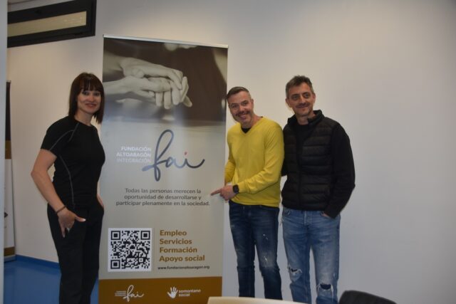 Imagen. Irene Villa, a la izquierda de la imagen, junto a un roll up de la Fundación AltoAragón Integración (FAI). A la derecha de la imagen aparecen David Serrano y David Mairal.