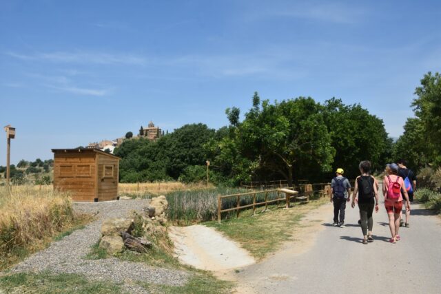 Imagen. De espaldas, grupo de senderistas de Somontano Social junto a la Balsa Caracruz de Bierge, rehabilitada por Somontano Social en una acción enmarcada en el Plan de Sostenibilidad Turística en Destino Saborea Guara Somontano de la Comarca de Somontano.