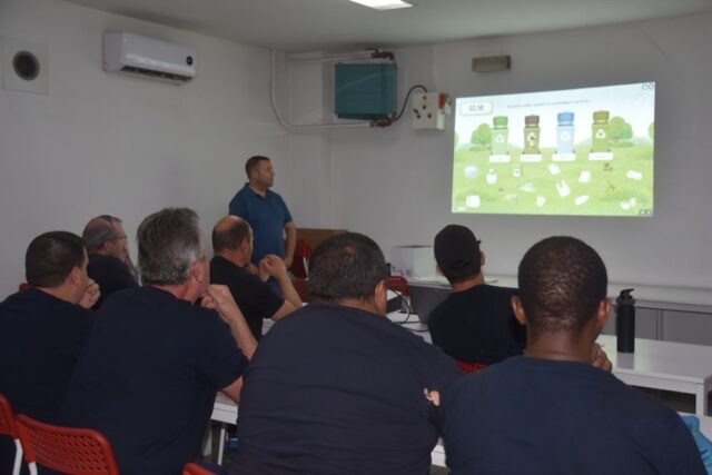 Imagen. De espaldas, grupo de trabajadores del Centro Logístico de Somontano Social atienden a las explicaciones en el Taller de Reciclaje y gestión de residuos.