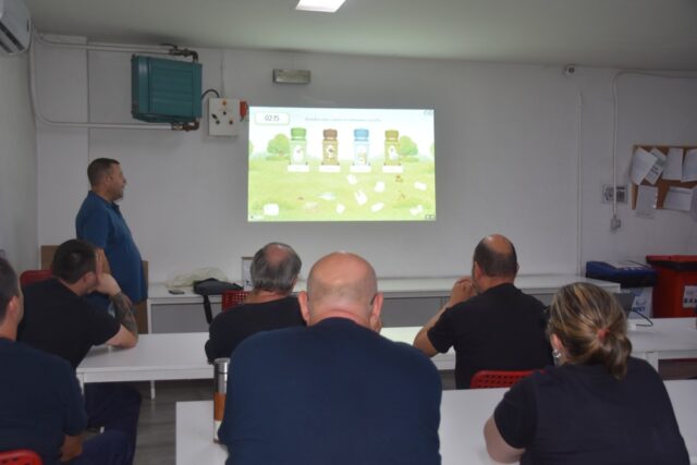 Imagen. De espaldas, grupo de trabajadores del Centro Logístico de Somontano Social atienden a las explicaciones en el Taller de Reciclaje y gestión de residuos.