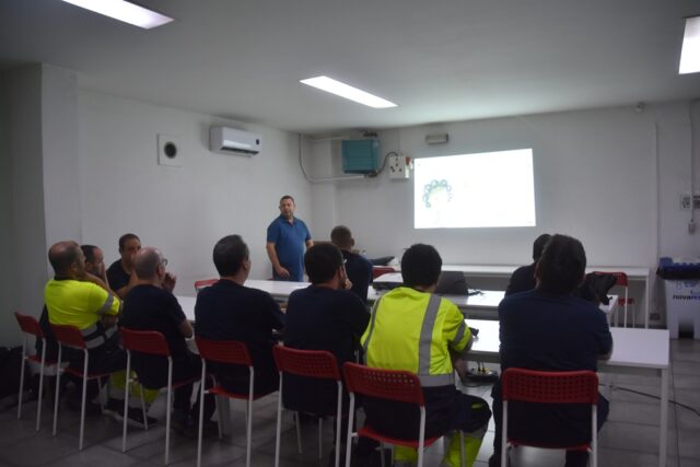Imagen. De espaldas, grupo de trabajadores del Centro Logístico de Somontano Social atienden a las explicaciones en el Taller de Reciclaje y gestión de residuos.