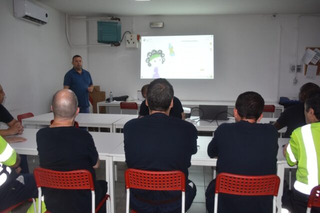 Imagen. De espaldas, grupo de trabajadores del Centro Logístico de Somontano Social atienden a las explicaciones en el Taller de Reciclaje y gestión de residuos.